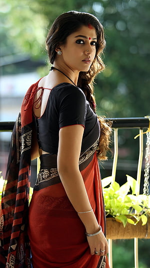 Nayanthara in a red and black sari with traditional jewelry on a balcony HD phone wallpaper