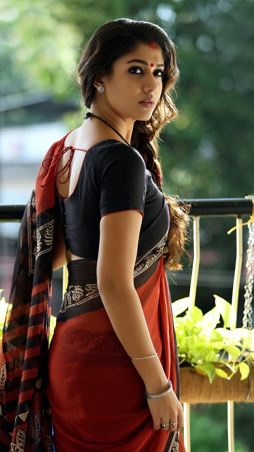 Nayanthara in a red and black sari with traditional jewelry on a balcony HD phone wallpaper