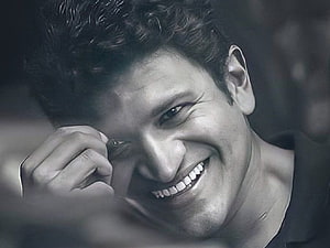 Puneeth Rajkumar Black and White Portrait with Warm Smile and Hand Gesture HD wallpaper