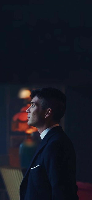 Cillian Murphy in a dark suit from Peaky Blinders, moody cinematic profile portrait with warm bokeh lighting HD phone wallpaper