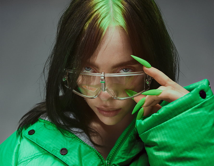 Billie Eilish in a vibrant green jacket and clear protective eyewear HD wallpaper
