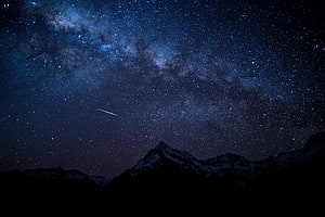 Milky Way Galaxy Arching Over Snow-Capped Mountain Peaks at Night HD wallpaper