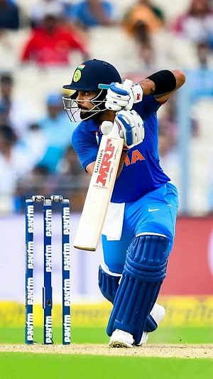 Virat Kohli in action during an ODI cricket match wearing the Indian national team blue kit HD phone wallpaper