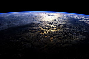 Earth From Space: Dark Ocean Surface With Sunlight Glare and Atmospheric Horizon HD wallpaper