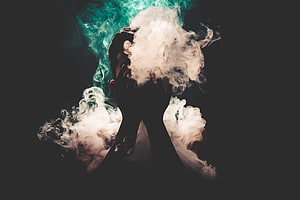 Silhouetted Hands Enveloped in Swirling White and Teal Smoke Against a Dark Background HD wallpaper