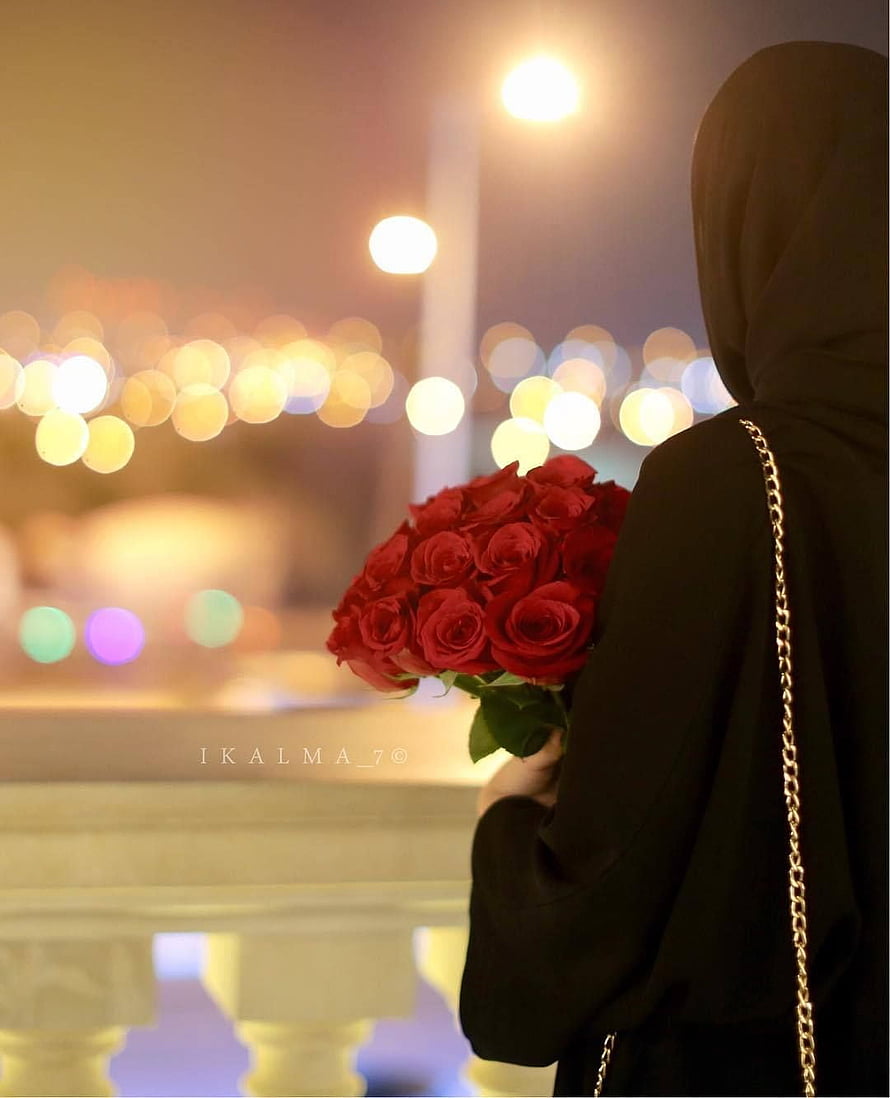 Woman in black hijab holding a bouquet of red roses against a bokeh city night background HD phone wallpaper