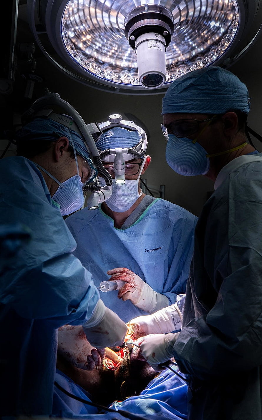Surgeons performing oral surgery under bright operating room lights HD phone wallpaper