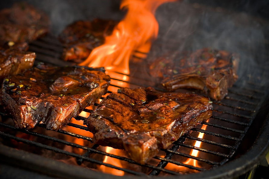 Sizzling seasoned steaks on a hot grill with open flames and rising smoke HD wallpaper