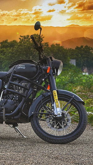 Black Royal Enfield Siva motorcycle parked on gravel road at golden hour sunset HD phone wallpaper