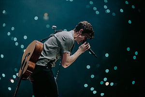 Shawn Mendes performing live on stage with acoustic guitar and microphone HD wallpaper