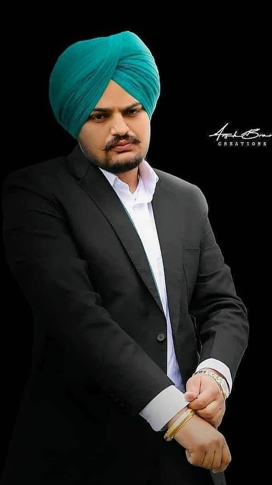 Sidhu Moose Wala in a black suit and teal turban with a serious expression HD phone wallpaper