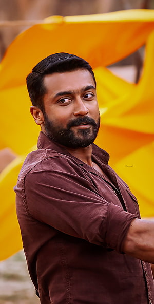 Suriya in Soorarai Pottru with a serious expression against a vibrant yellow backdrop HD phone wallpaper