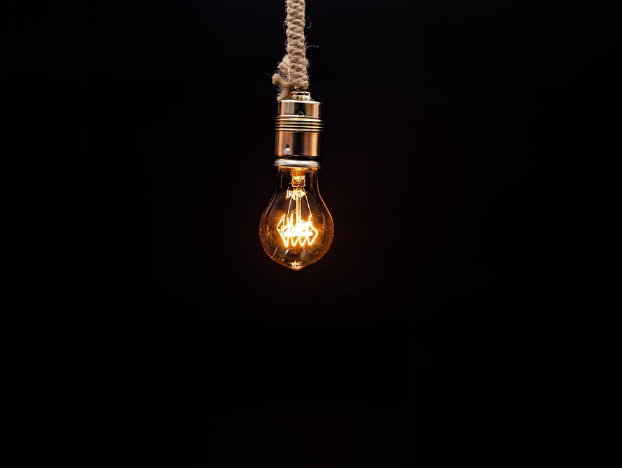 Glowing Edison bulb suspended by a rope against a dark background HD wallpaper