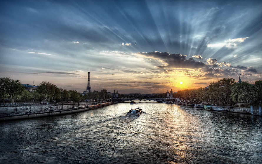Sunset over the Seine River in Paris with the Eiffel Tower and dramatic sky rays HD wallpaper