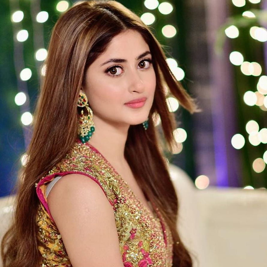 Sajal Aly in ornate gold embroidered outfit with festive bokeh lights HD phone wallpaper
