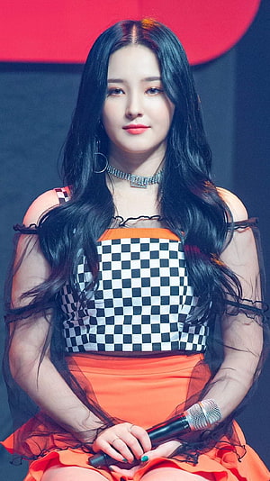 Nancy from MAMAMOO in a checkered and orange stage outfit holding a microphone HD phone wallpaper