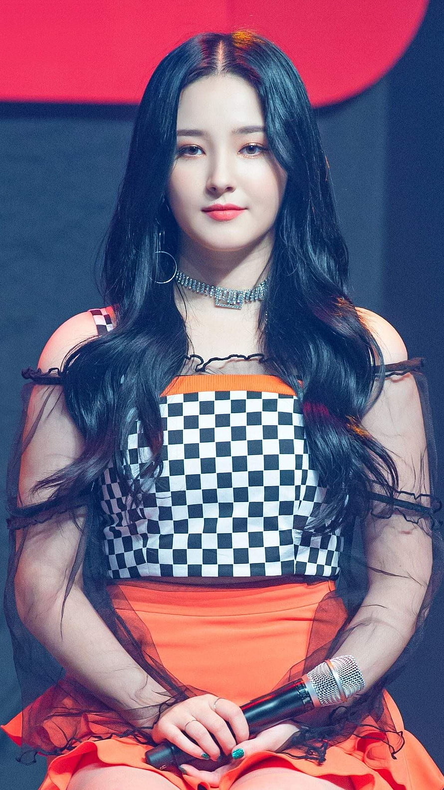 Nancy from MAMAMOO in a checkered and orange stage outfit holding a microphone HD phone wallpaper