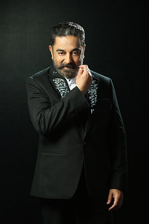 Kamal Haasan in a black tuxedo with geometric lapel details against a dark studio backdrop HD phone wallpaper