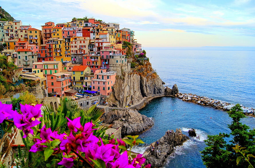 Colorful cliffside village in Italy overlooking the Mediterranean Sea with vibrant bougainvillea in the foreground HD wallpaper
