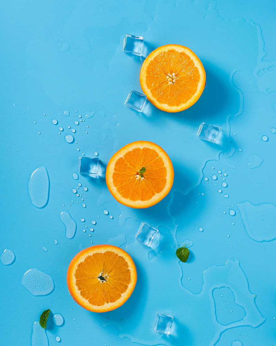 Fresh Orange Slices with Ice Cubes and Mint on a Vibrant Blue Background HD phone wallpaper