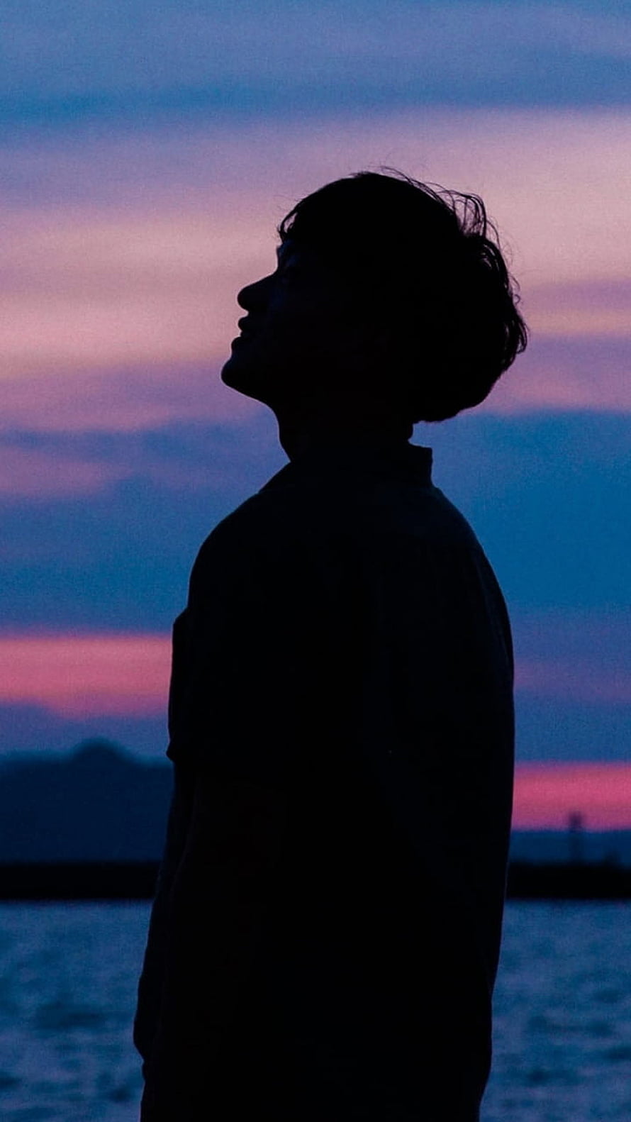 Silhouette of a young man gazing upward against a twilight sky with pink and blue hues over a calm body of water, boy, silhouette, sunset, sky PC and Mac, Boy Pic HD phone wallpaper