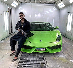 Karan Aujla posing with a green Lamborghini in a paint booth HD wallpaper