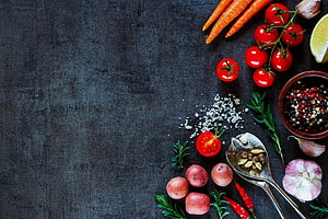 Fresh organic vegetables and spices arranged on a dark slate surface with herbs and garlic HD wallpaper