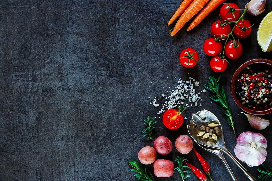 Fresh organic vegetables and spices arranged on a dark slate surface with herbs and garlic HD wallpaper
