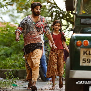 Dulquer Salman and young girl walking through lush greenery in traditional Indian attire HD phone wallpaper