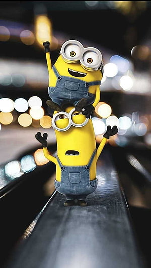 Two Minions Stacked on a Conveyor Belt with Bokeh City Lights in the Background HD phone wallpaper