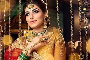 Elegant Indian Bride in Gold Lehenga with Emerald Jewelry and Traditional Headpiece HD wallpaper