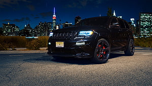 Black Jeep Grand Cherokee SRT with red brake calipers parked on a city street at night HD wallpaper