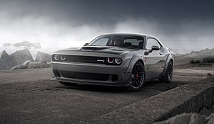 Dodge Challenger SRT muscle car parked on a rugged coastal cliff under a dramatic overcast sky HD wallpaper