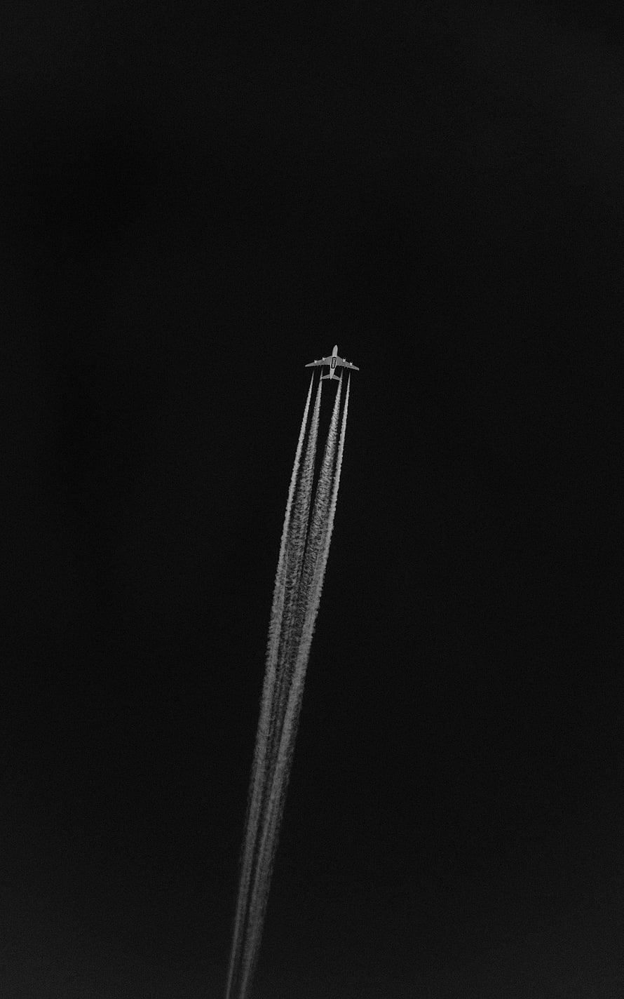 Minimalist Black and White Airplane Leaving Contrails Against a Dark Sky HD phone wallpaper