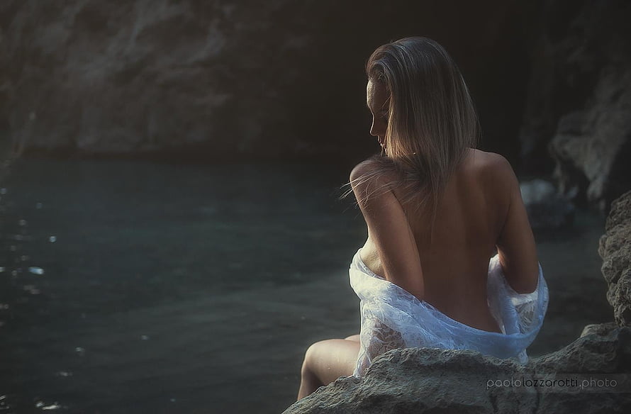 Woman in White Lace Sitting on Rocky Shore at Dusk HD wallpaper