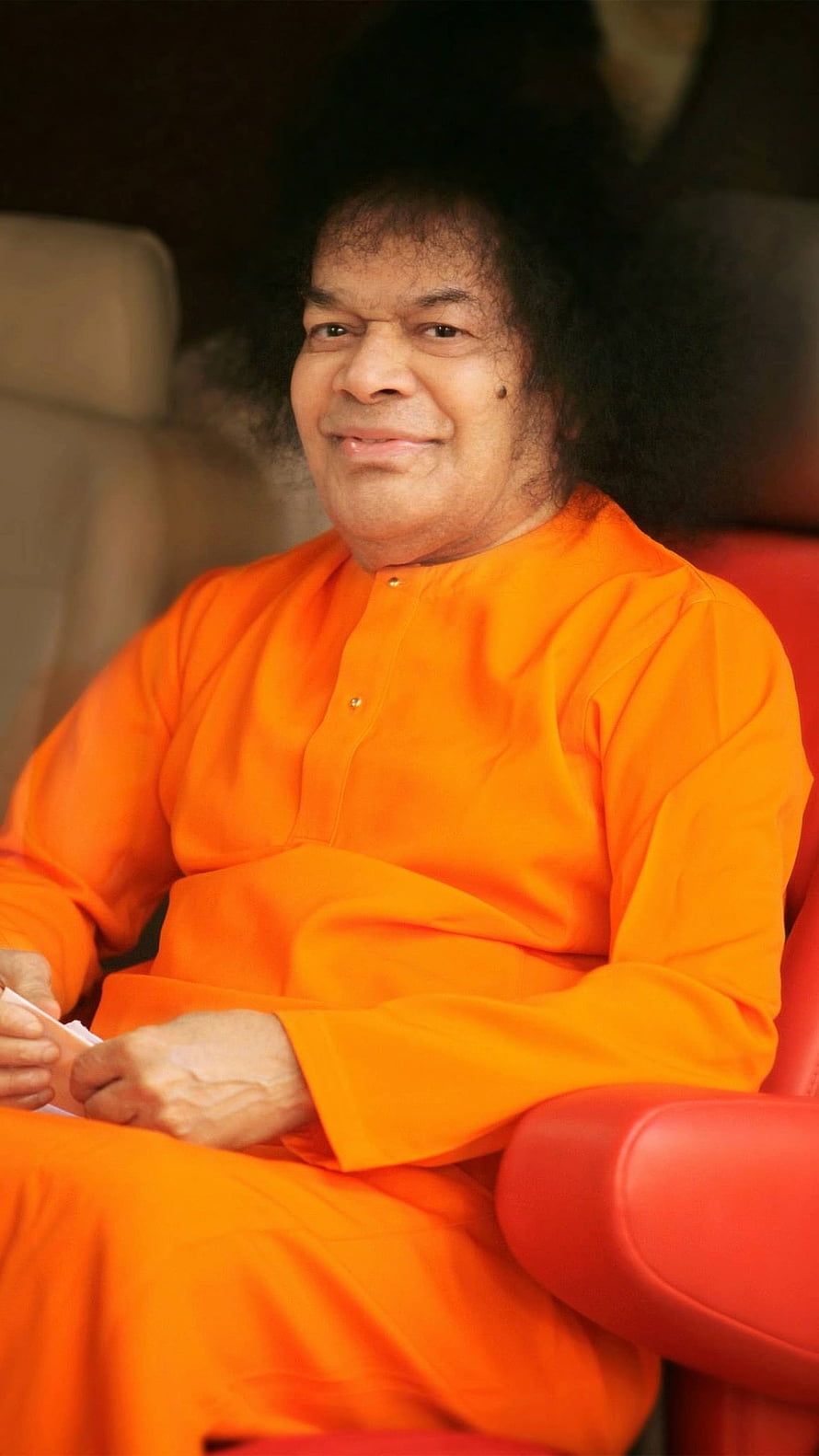 Sathya Sai Baba Portrait in Orange Robe Seated in Red Chair HD phone wallpaper