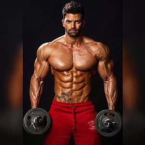 Muscular Male Bodybuilder Holding Dumbbells in Red Sweatpants HD phone wallpaper