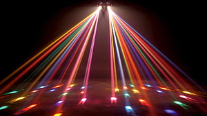 Vibrant multicolored laser beams radiating from a central source in a dark room HD wallpaper