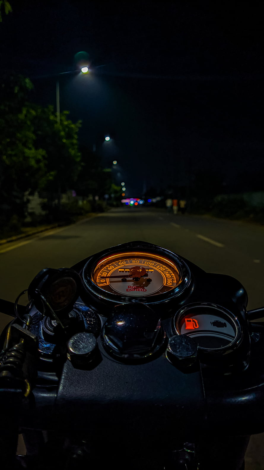 Royal Enfield motorcycle dashboard glowing on a dark night road with streetlights HD phone wallpaper