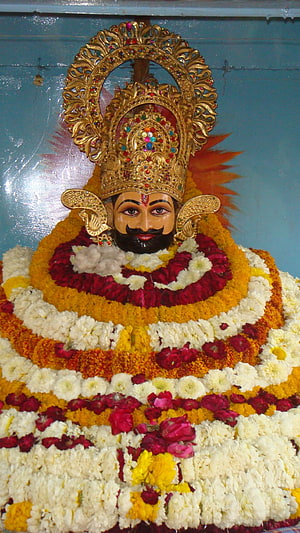 Khatu Shyam Ji adorned in vibrant floral garlands and ornate golden crown HD phone wallpaper
