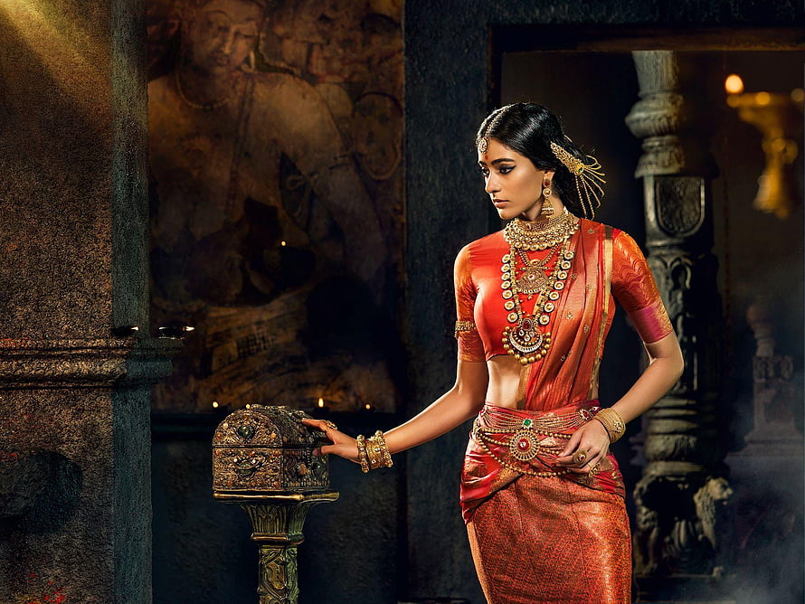 Elegant Woman in Traditional Red Saree with Gold Jewelry in Ancient Temple Setting HD wallpaper