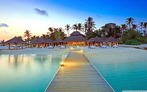Tropical Maldives Resort at Dusk with Wooden Boardwalk and Thatched Huts HD wallpaper