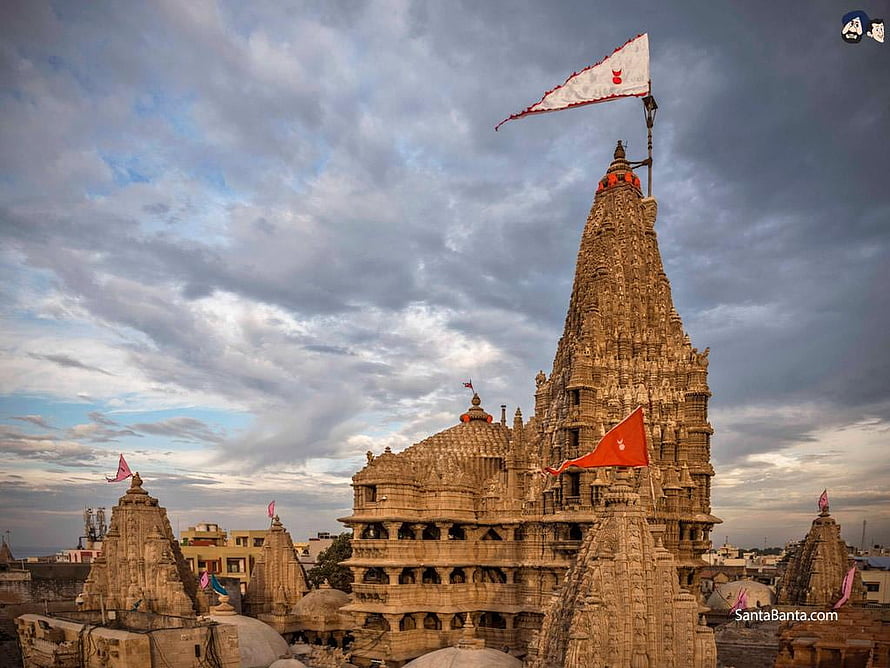 Dwarkadhish Temple in Gujarat with ornate stone shikhara and fluttering flags under a dramatic cloudy sky HD wallpaper