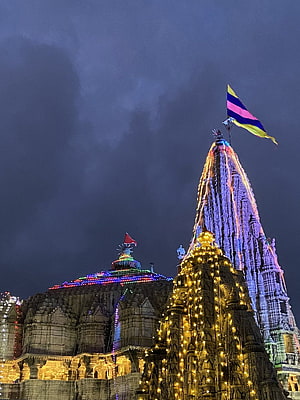 Shri Dwarkadhish Temple illuminated with festive lights and colorful flags at night HD phone wallpaper