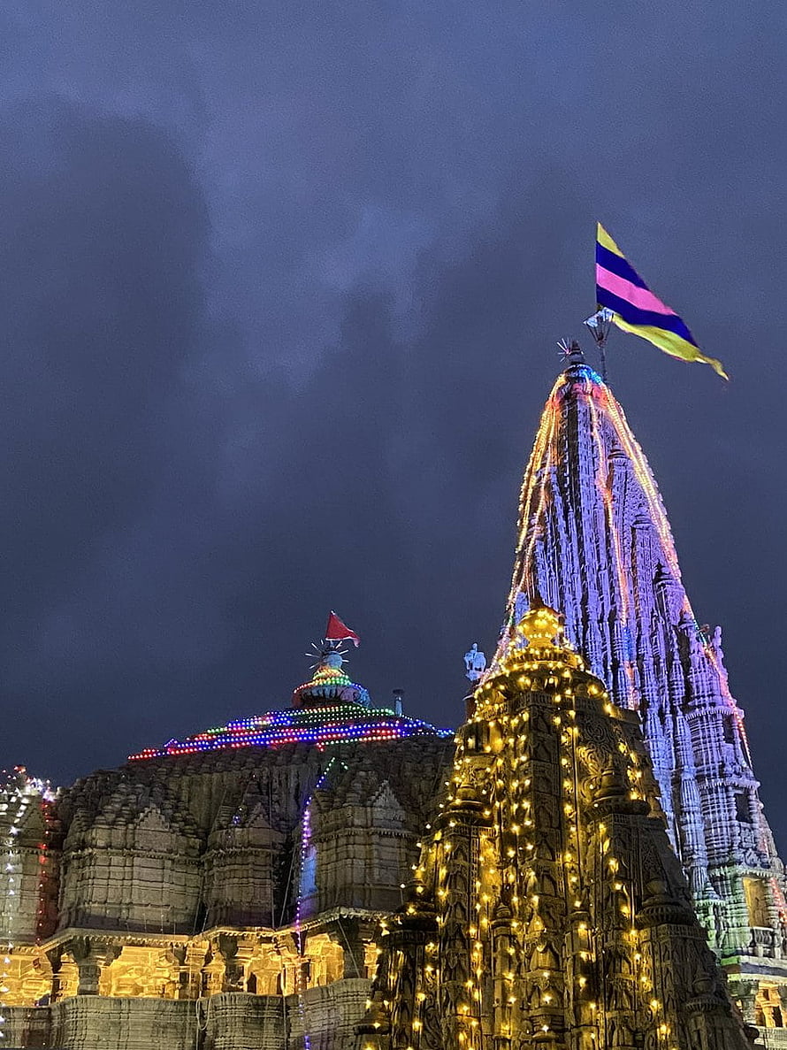 Shri Dwarkadhish Temple illuminated with festive lights and colorful flags at night HD phone wallpaper