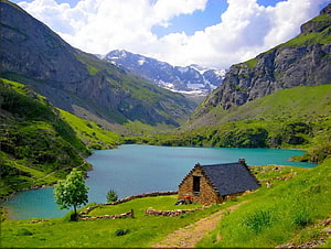 Alpine mountain lake with stone cottage nestled in green valley HD wallpaper