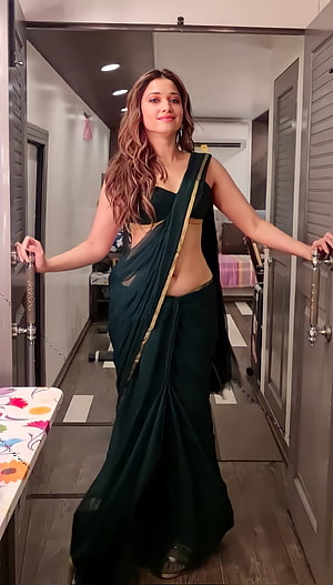 Tamannaah Bhatia in a dark green saree with gold border standing in a modern interior hallway HD phone wallpaper