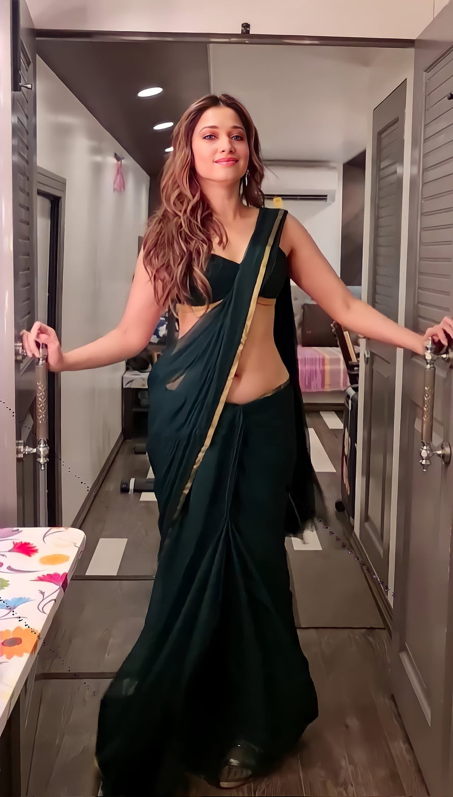 Tamannaah Bhatia in a dark green saree with gold border standing in a modern interior hallway HD phone wallpaper