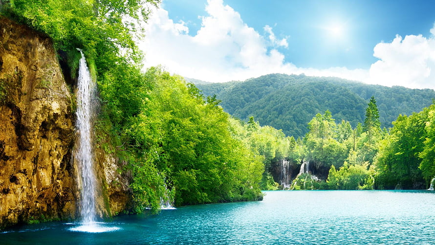 Serene Waterfall Cascading Into Turquoise Lake Surrounded By Lush Green Forest HD wallpaper