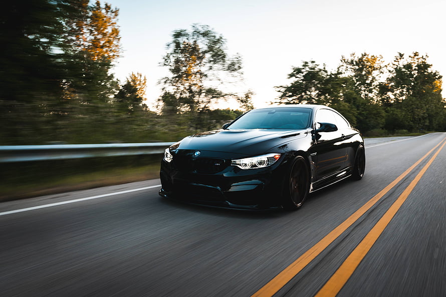 Black BMW M4 Coupe Driving on a Scenic Highway at Sunset HD wallpaper